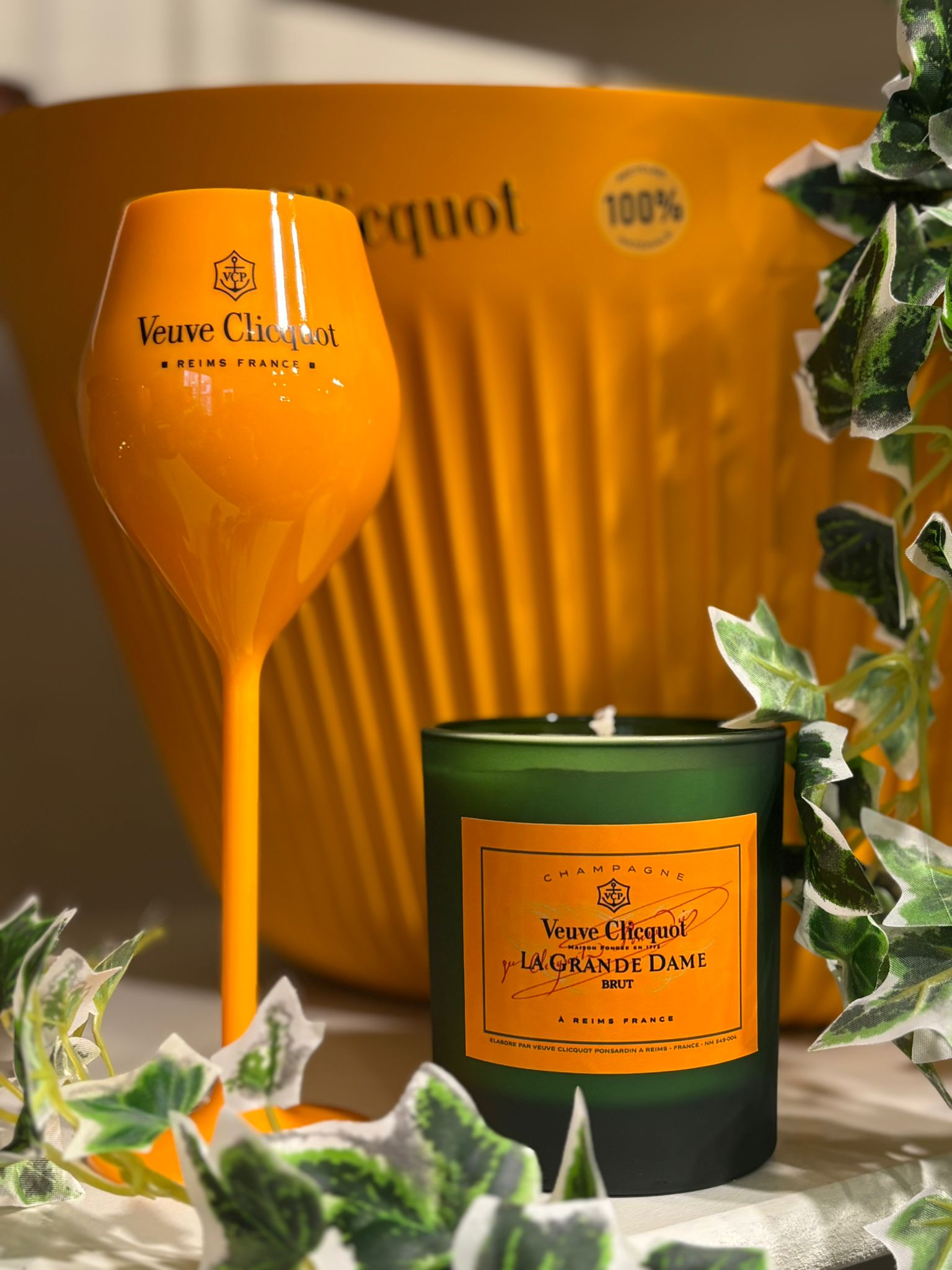 Veuve Clicquot candle with wine glass and green leaves in the foreground